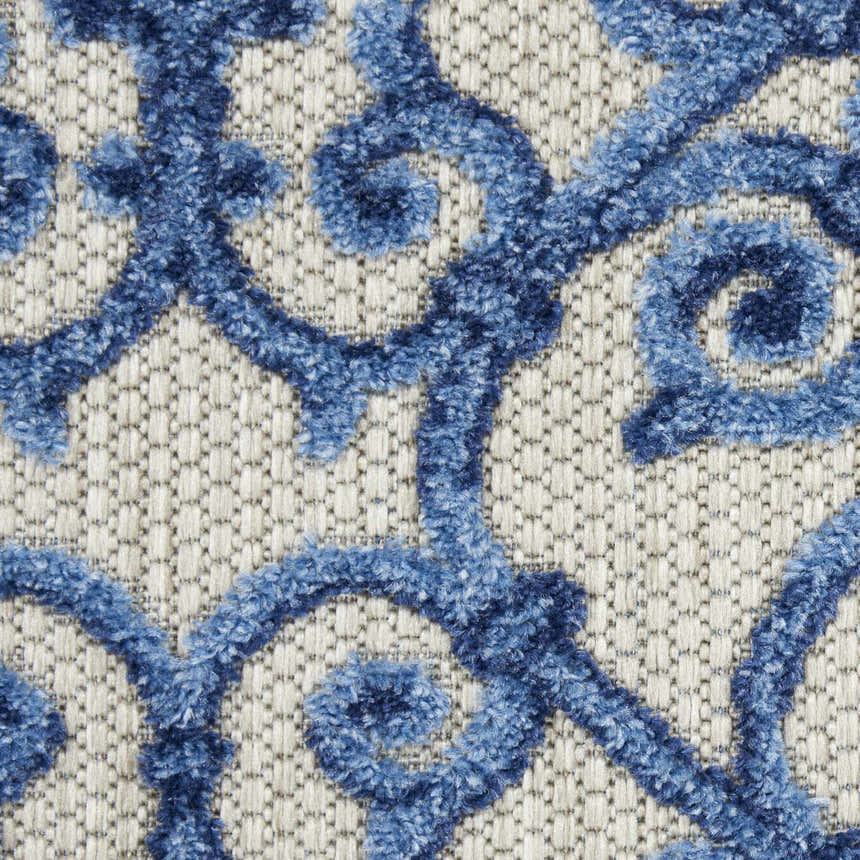 Close-up of the Nourison Aloha Grey Blue rug, featuring a textured blue swirl pattern on a woven gray background.