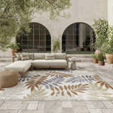 Outdoor patio with beige sofa and Nourison Aloha Blue Mocha rug with leaf pattern.