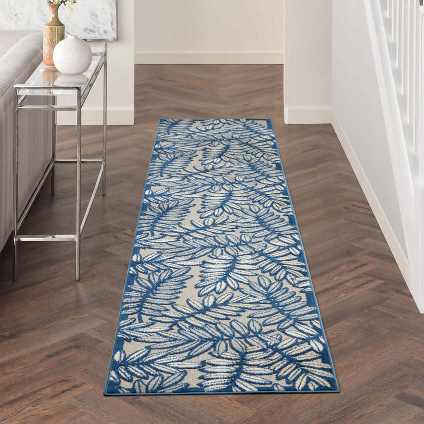 Hallway with Nourison Aloha Ivory Navy Tropical runner rug, wood floors, console table, and neutral decor.