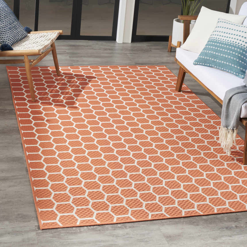 Modern patio scene with a Nourison Twist Coral rug featuring a geometric honeycomb pattern.