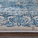 Close-up of the Feizy Cadiz rug showing its blue, gray, and gold abstract pattern and textured, machine-made construction. Pile