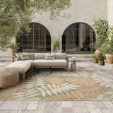 Outdoor patio with a beige sectional sofa and Nourison Aloha Sage Rose Rug featuring a leaf pattern.