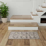 Entryway with wood floors and Nourison Oushak Home Charcoal Vintage Area Rug, stairs, and potted plant.