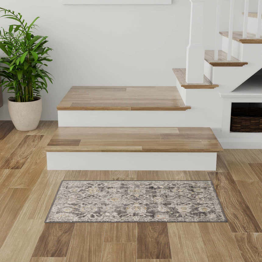 Entryway with wood floors and Nourison Oushak Home Charcoal Vintage Area Rug, stairs, and potted plant.
