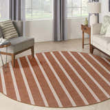 Living room scene with a round Nourison Positano Terracotta Ivory rug, gray chair, and light sofa. Striped rug adds a modern touch.