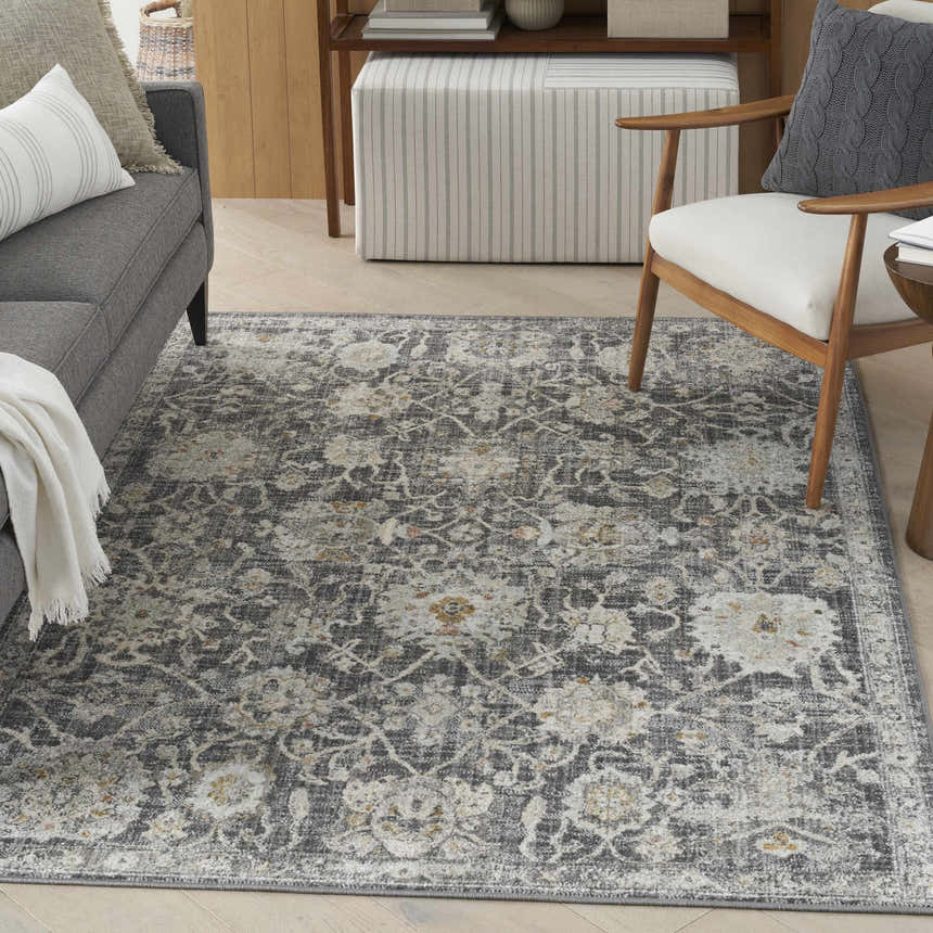 Living room scene with gray sofa and Nourison Oushak Home Charcoal Vintage Area Rug featuring taupe floral pattern.
