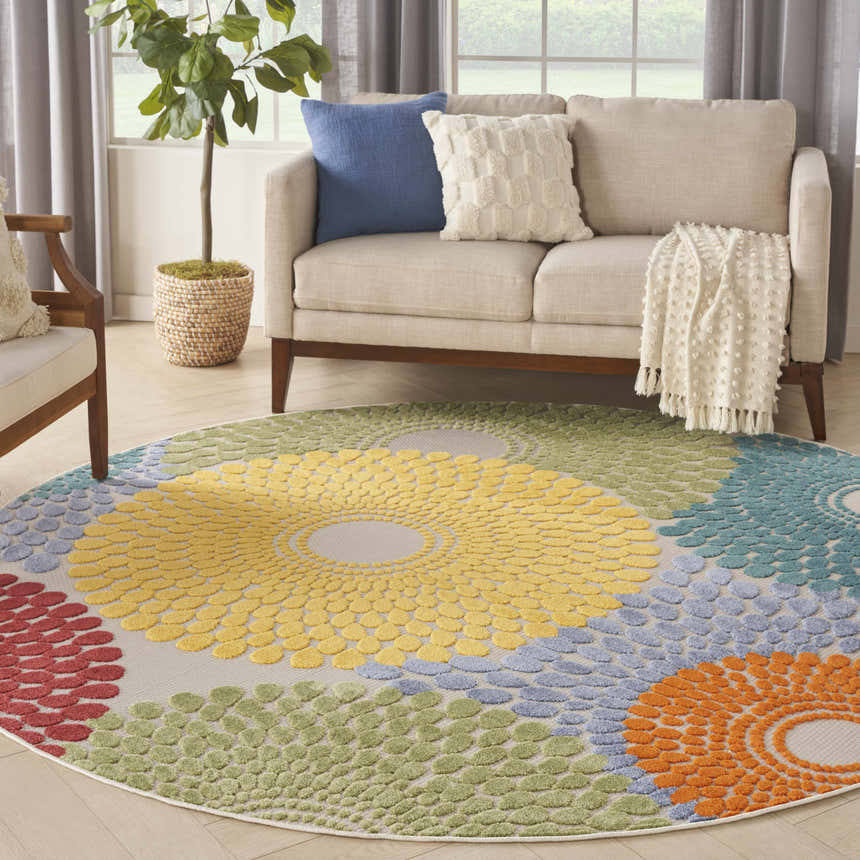 Living room scene with a round Nourison Aloha Multicolor rug featuring a floral pattern in yellow, green, blue, red, and orange.