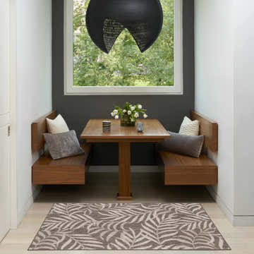 Breakfast nook with Nourison Garden Oasis Mocha Tropical Area Rug, wood table, and bench seating.