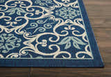 Close-up of the Nourison Caribbean Navy Contemporary Area Rug with floral and scroll pattern on dark wood floor.
