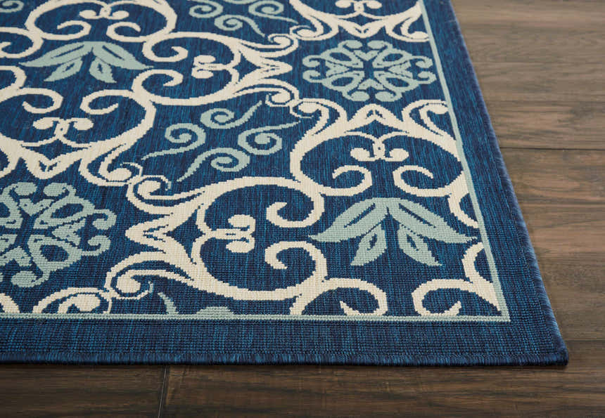 Close-up of the Nourison Caribbean Navy Contemporary Area Rug with floral and scroll pattern on dark wood floor.