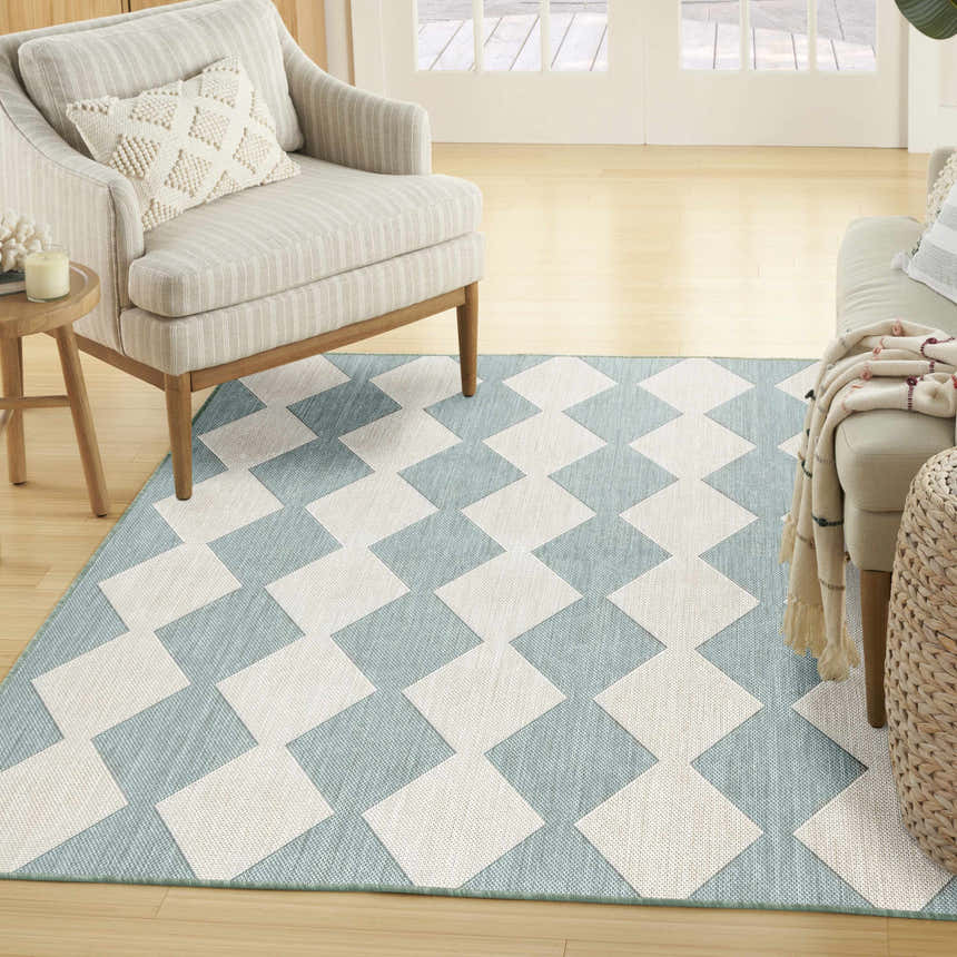 Living room scene with a Nourison Positano Aqua Modern Area Rug. Aqua and white geometric diamond pattern. Neutral furniture.