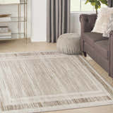 Living room scene with a Nourison Serenity Home Mocha Ivory rug, brown sofa, and neutral decor.