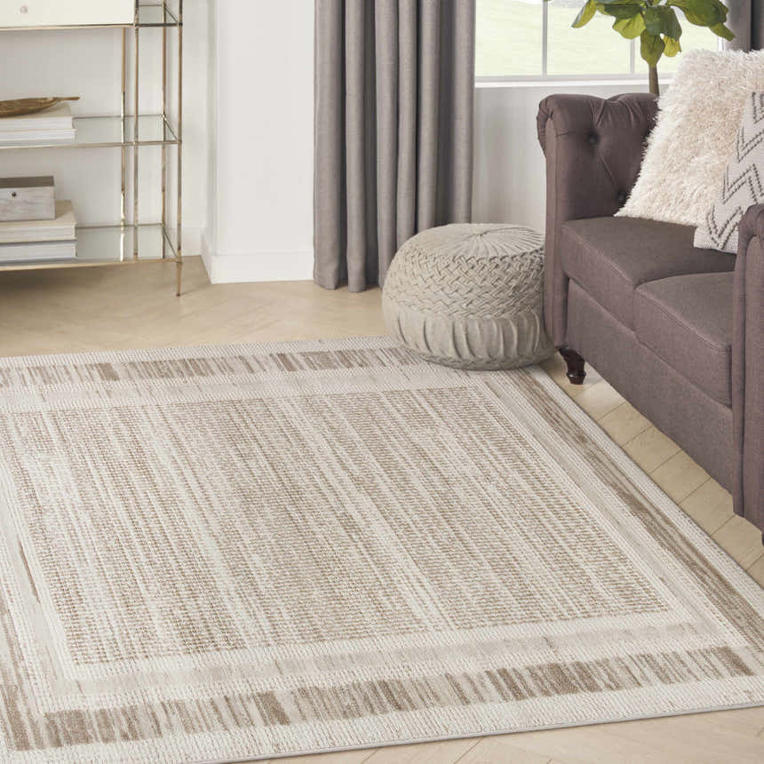 Living room scene with a Nourison Serenity Home Mocha Ivory rug, brown sofa, and neutral decor.