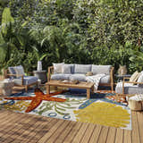 Outdoor patio with gray furniture and Nourison Aloha Multicolor rug featuring starfish and seashell designs.