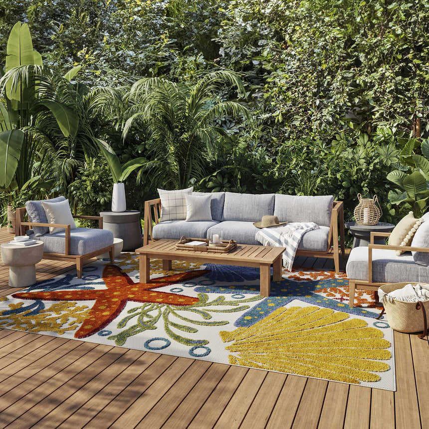 Outdoor patio with gray furniture and Nourison Aloha Multicolor rug featuring starfish and seashell designs.