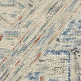Close-up of the Nourison Interlock Rug. Blue, cream, and tan wool rug shows a textured, looped, geometric pattern.
