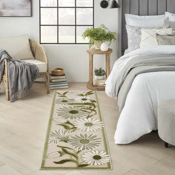 Bedroom scene with a Nourison Aloha Ivory Green Outdoor Area Rug runner featuring a floral design.