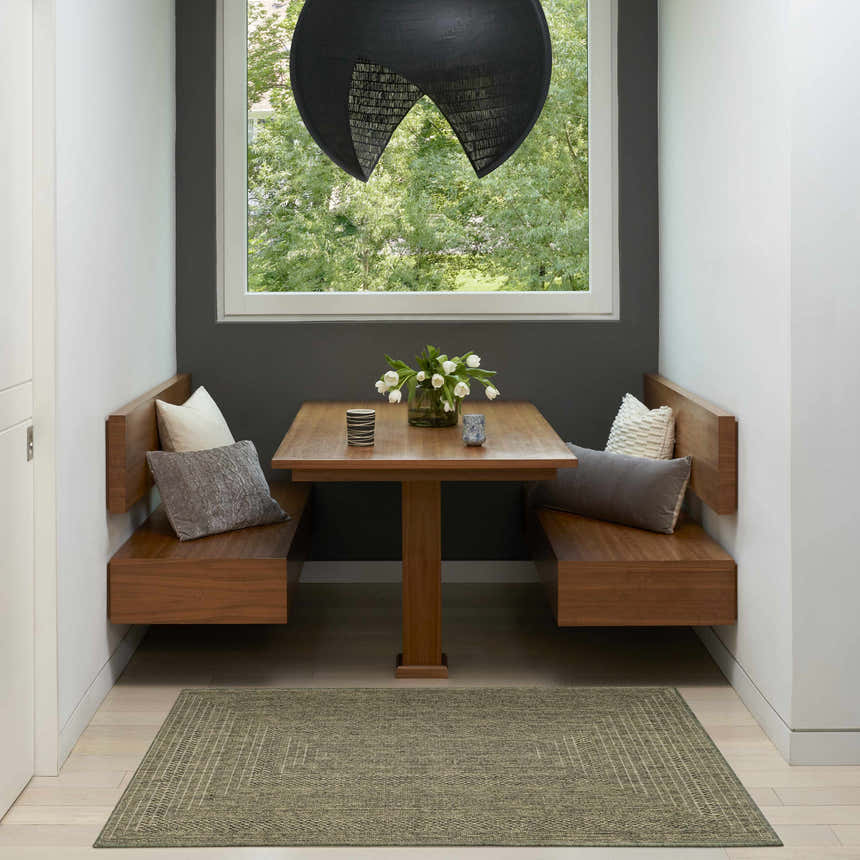 Modern breakfast nook with wood benches and a Nourison Tulum Olive Outdoor Area Rug on light wood floors.