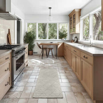 Light-filled kitchen with a Nourison Wool Haven Grey runner rug, wood cabinets, and a breakfast nook.