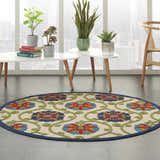 Modern living room with a round Nourison Aloha Blue Multicolor rug, plants, and city view.