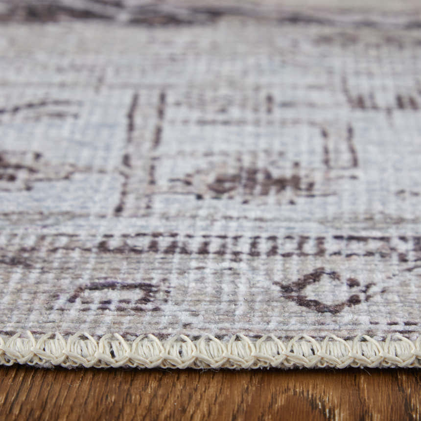 Close-up of the tan, ivory, and gray Feizy Percy rug showing the medallion pattern and braided edge detail. Pile