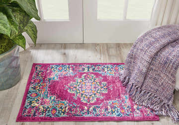 Entryway with Nourison Passion Fuchsia rug, wood floor, white door, potted plant, and a cozy purple throw blanket.