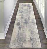 Hallway with Nourison Rustic Textures Blue Ivory runner rug on dark wood floor, white walls and door.