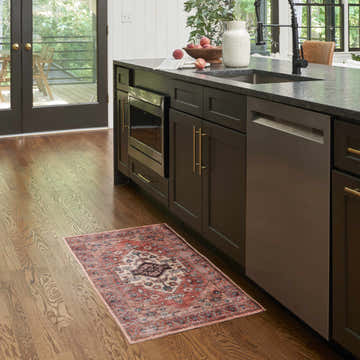 Kitchen scene with Nourison Grand Rust Multicolor vintage rug on hardwood floor, under dark cabinets.