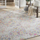 Living room scene with Nourison Damask Multicolor Bohemian rug, gray chair, ottoman, and light wood floors.