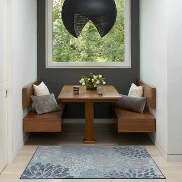 Dining nook with wood benches and a Nourison Garden Oasis Navy Tropical Area Rug.