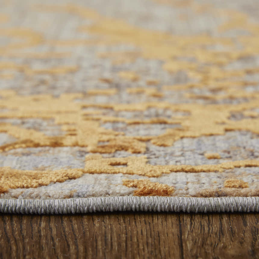 Close-up of Feizy Pryor rug showing gold abstract design, gray base, and textured pile. Pile