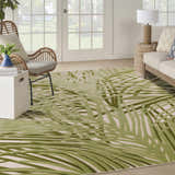 Coastal living room with a Nourison Aloha Ivory Green Outdoor Area Rug, wicker chair, and light wood sofa.