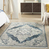 Bedroom scene with blue and gray Nourison Carina vintage rug, bed, wood floors, and modern cabinet.