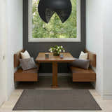 Modern dining nook with Nourison Horizon Charcoal rug, wood benches, and a view to the outdoors.