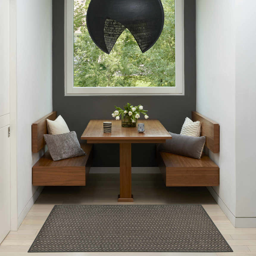 Modern dining nook with Nourison Horizon Charcoal rug, wood benches, and a view to the outdoors.