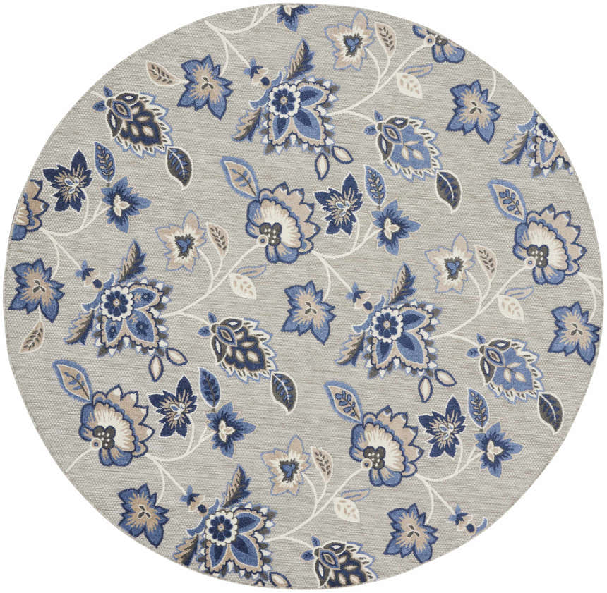 Close-up of a round Nourison Aloha Blue Grey Outdoor Area Rug with a blue and taupe floral pattern on a gray background.
