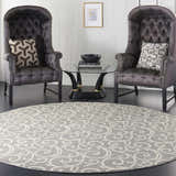Living room scene with a round Nourison Grafix Grey rug, two dark wingback chairs, and a glass coffee table.
