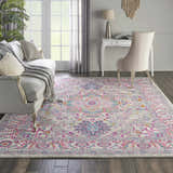 Living room scene with a Nourison Passion Light Grey Pink rug, sofa, desk, and chair. Bohemian style.
