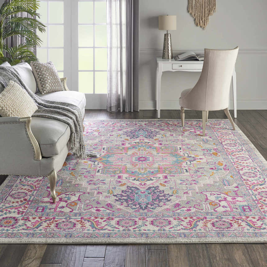 Living room scene with a Nourison Passion Light Grey Pink rug, sofa, desk, and chair. Bohemian style.