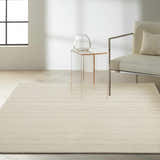 Minimalist living room scene with Calvin Klein Halo Ivory rug, clear side table, and modern chair.