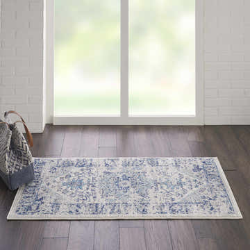 Bright room scene with a Nourison Tranquil Ivory Light Blue Vintage Indoor Area Rug on dark wood floors.
