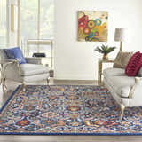 Living room scene with Nourison Passion Blue Multicolor Rustic Area Rug, gray seating, and colorful artwork.