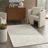 Modern living room with a Nourison Avra Ivory rug, wood dresser, and neutral armchairs.