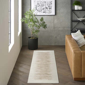 Modern living room with a DKNY Grand Street Ivory Taupe rug, leather sofa, plant, and abstract art.