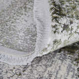 Close-up of Feizy Cadiz Modern Ikat rug showing gray, green, and silver abstract pattern and fringe detail. Fold
