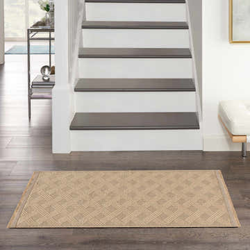 Entryway scene with a Nourison Jute Natural rug in brick red, placed on dark wood floors near stairs.