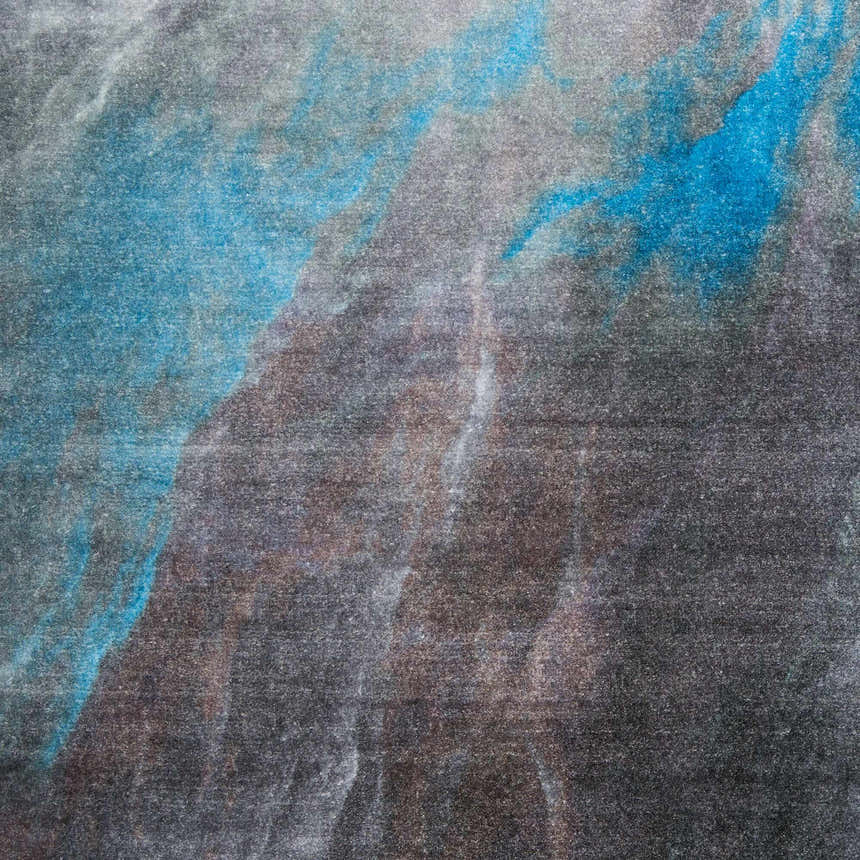 Close-up of Nourison Le Reve rug, charcoal gray with abstract blue and taupe pattern. Mid-century modern style.