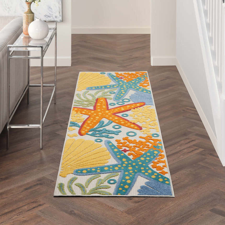 Hallway with Nourison Aloha runner rug. Coastal style with starfish and shells on a herringbone wood floor.