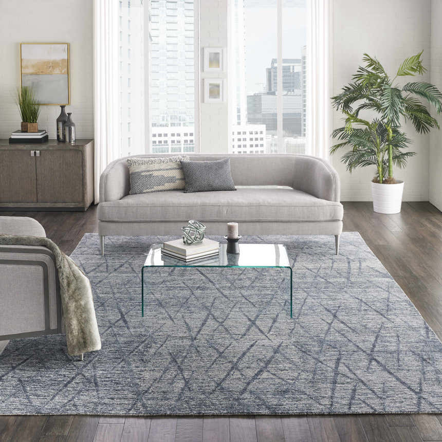Modern living room with grey sofa, glass table, and Nourison OCEAN Indigo area rug.