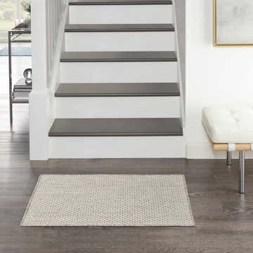 Hallway scene with Nourison Courtyard Ivory Silver rug, wood floors, white stairs, and modern white bench.
